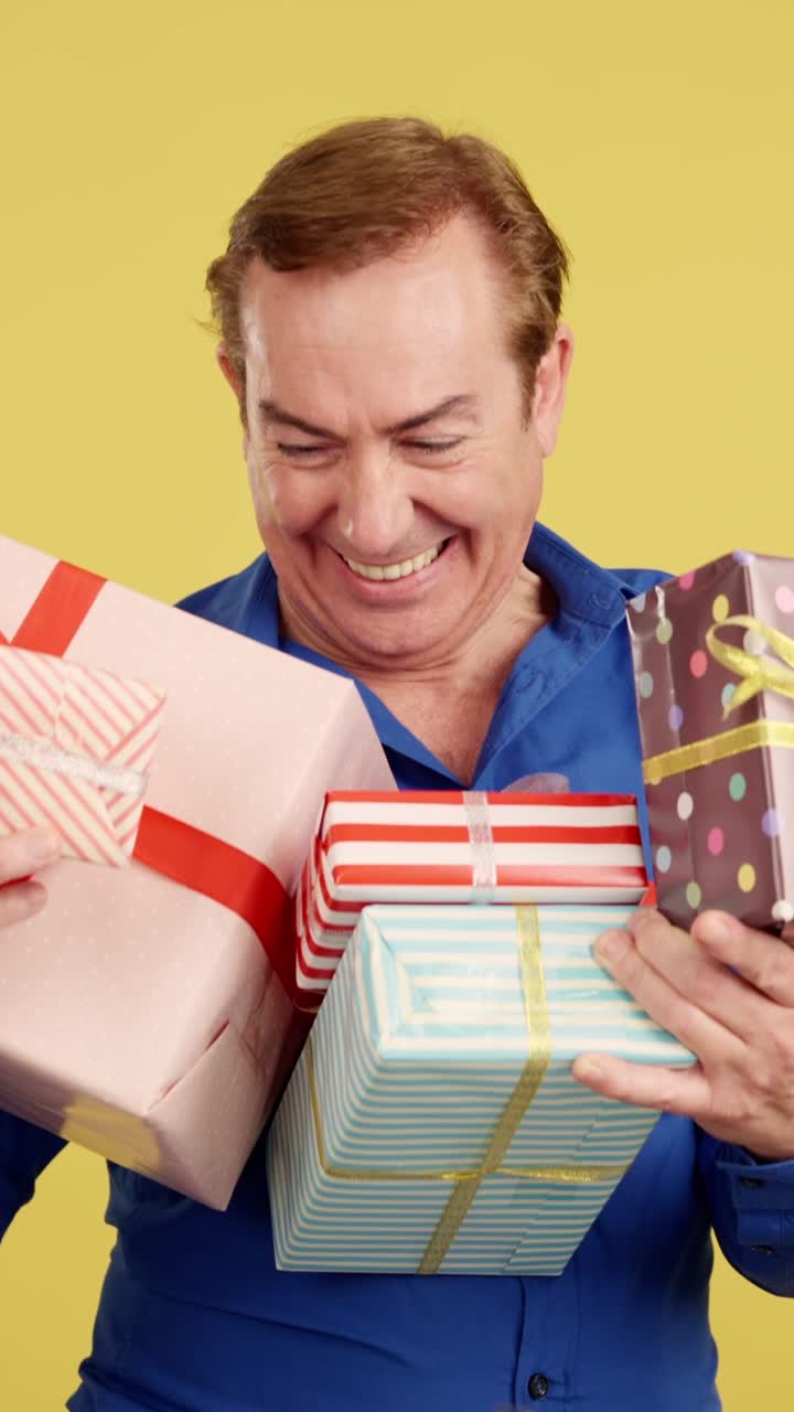 A happy man holding a stack of colorful wrapped gifts