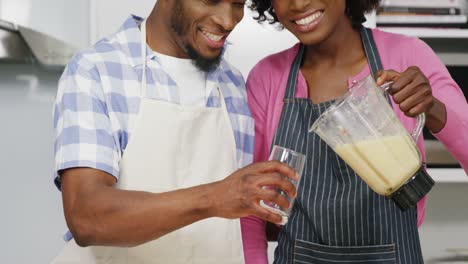 Happy-man-and-woman-preparing-juice-in-juicer