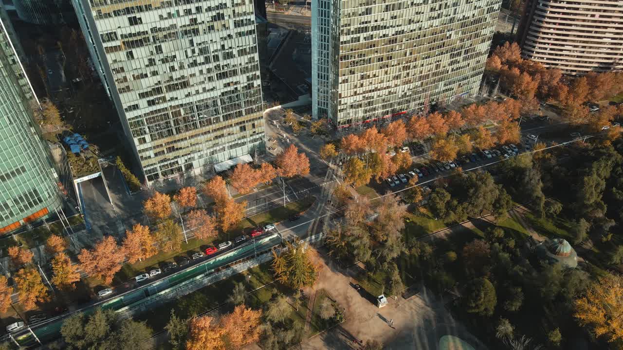 autos estacionados y tráfico de carreteras en movimiento entre el parque recreativo y las modernas estructuras de oficinas de nueva las condes en santiago, chile