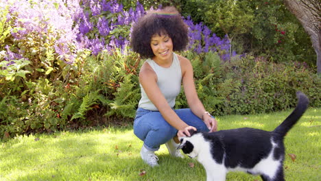 petting black and white cat, woman enjoying time in garden