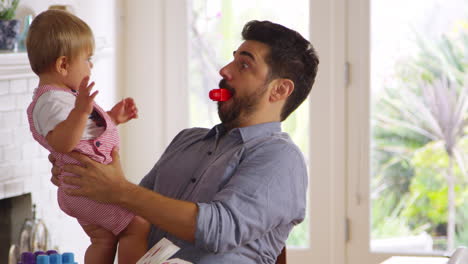 father sits at table and plays with baby son at home