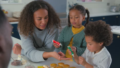 Family-With-Children-In-Kitchen-Decorating-Cupcakes-Together