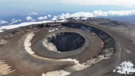 drone shot of uhuru peak on mount kilimanjaro with the volcanic crater below. downward angle aerial shot