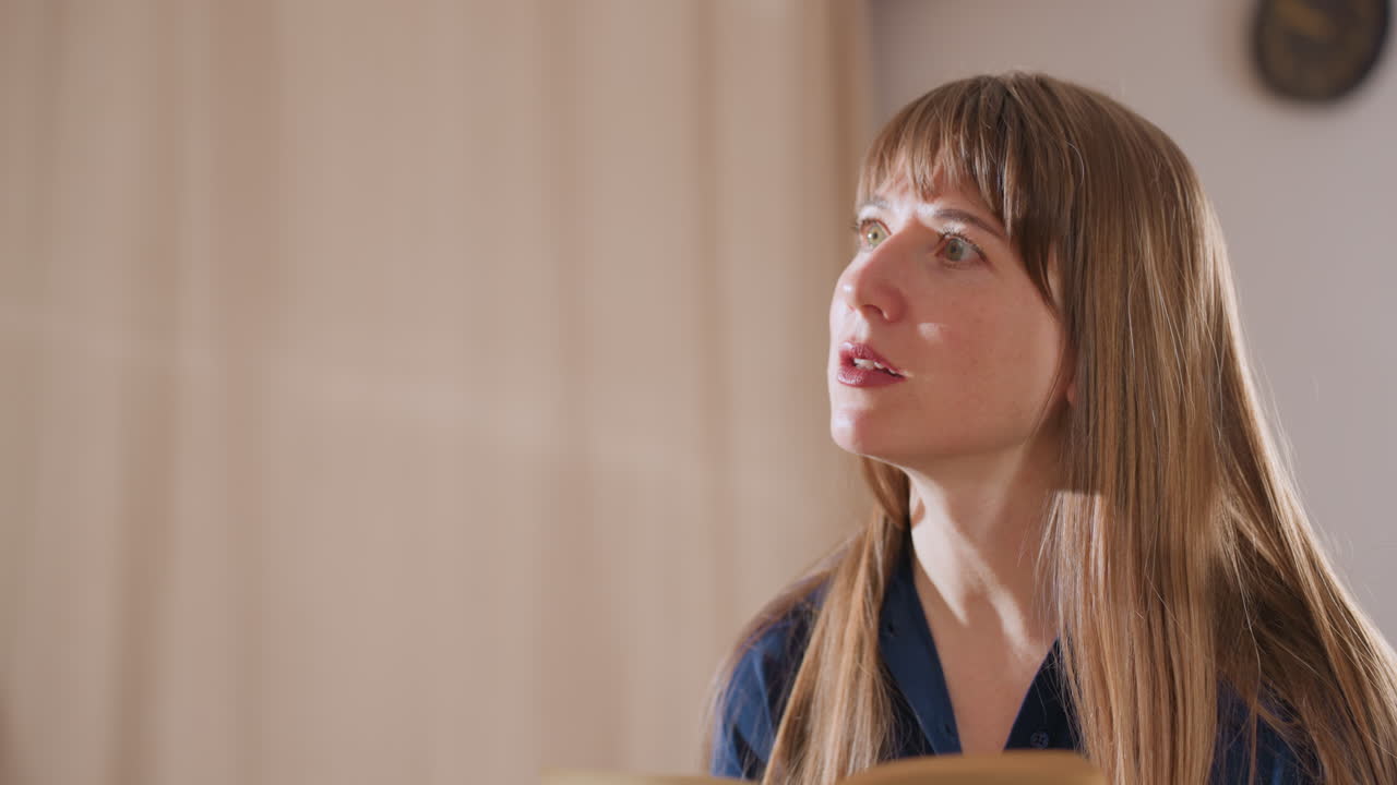 Wellness guide with long hair reads from notebook while speaking to client in softly lit room, conveying calm, professionalism, and focus in therapeutic or coaching environment