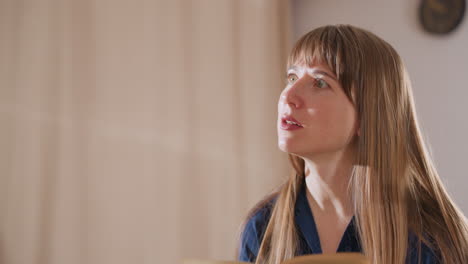 wellness guide with long hair reads from notebook while speaking to client in softly lit room, conveying calm, professionalism, and focus in therapeutic or coaching environment