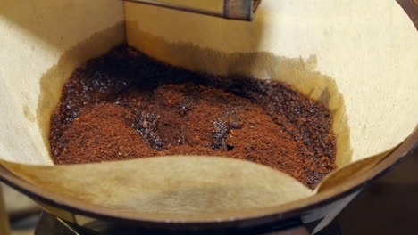 close-up: hot water pours into cone filter full of rich ground coffee