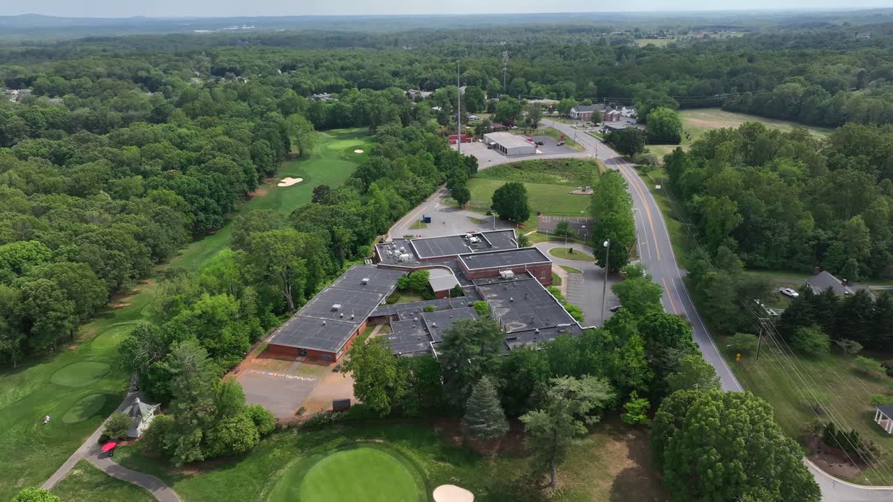 Boonsboro Elementary School beside Boonsboro Country Club in Lynchburg, Virginia. Sunny day with green spring trees. Aerial orbit wide shot.