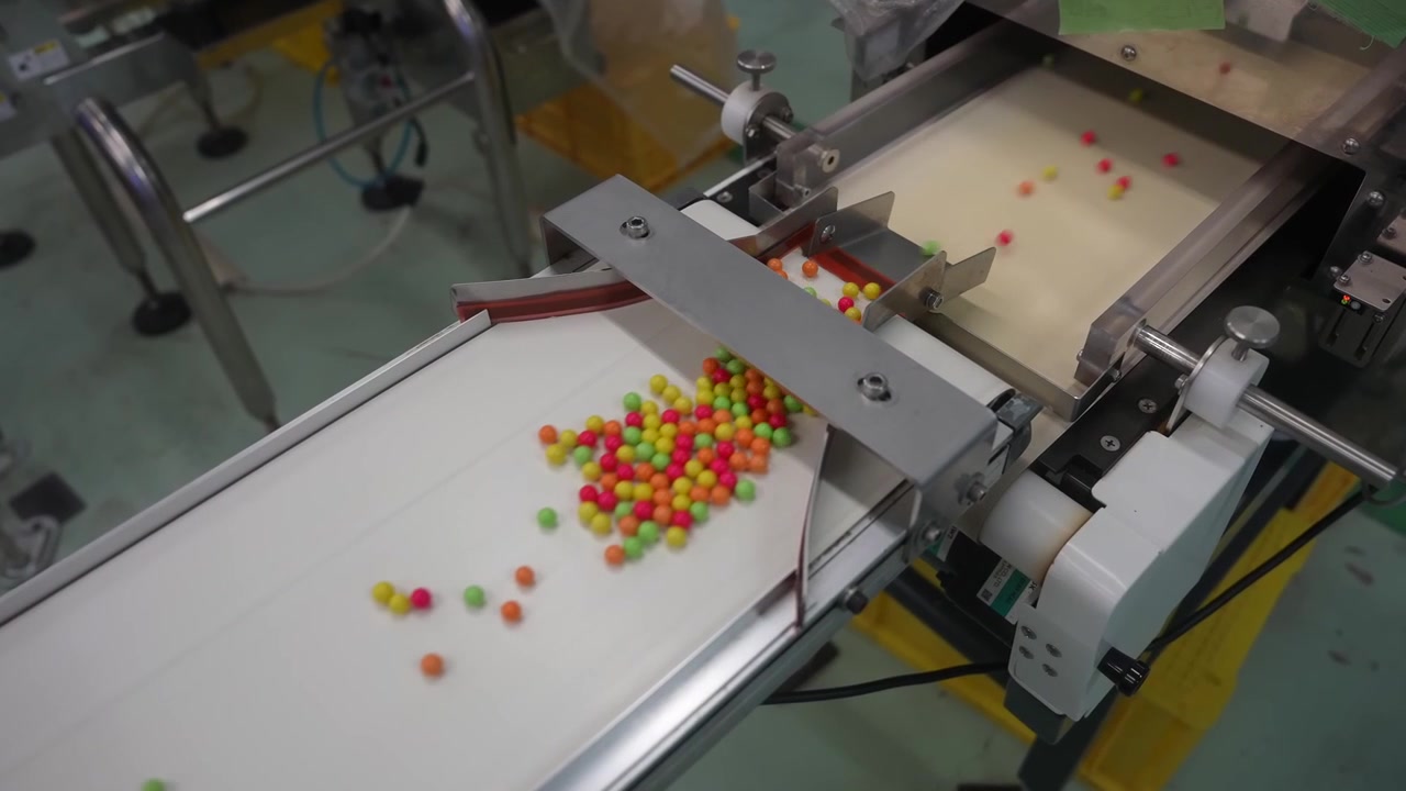 Colorful coated pellets moving along a conveyor on an inspection line