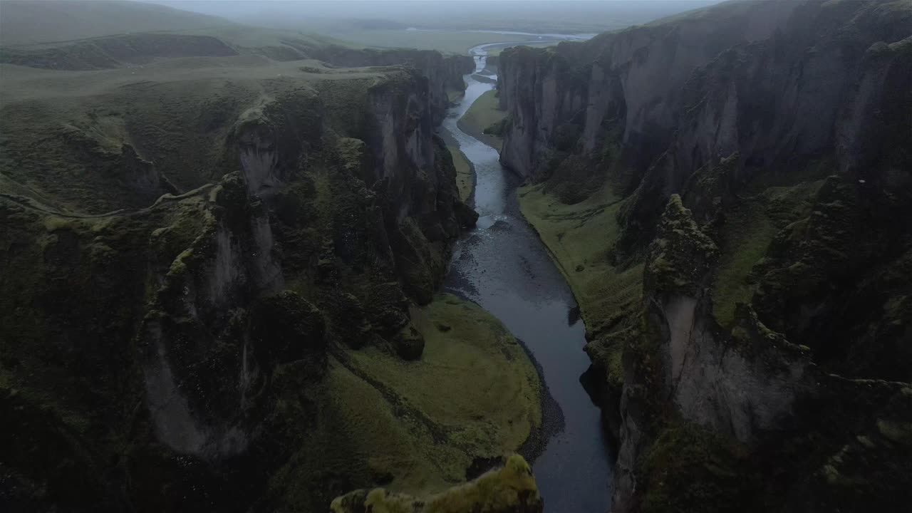 Volo sopra e attraverso il canyon nuvoloso di Fjaðrárgljúfur in Islanda 4K