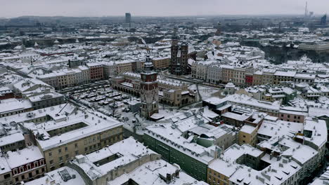snow-covered old town (krakow city center - main square, sukiennice - cloth hall and town hall) at magic morning with sunlight, krakow, poland