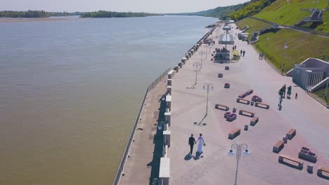 just married couple walks along river waterfront aerial