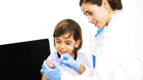 dentista mostrando a un paciente joven cómo cepillarse los dientes