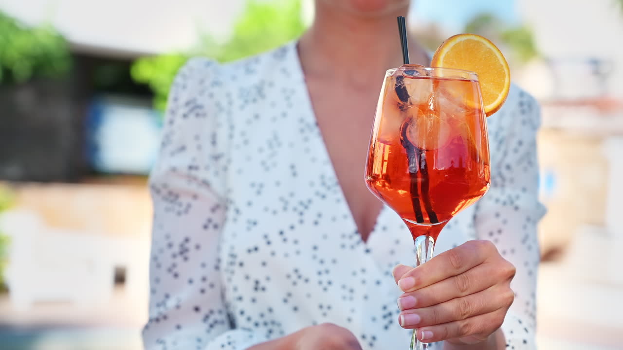 Frau hält einen Cocktail mit Eis und einer Orangenscheibe in Griechenland