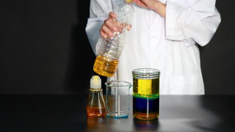 un científico demuestra un experimento de densidad líquida, creando capas coloridas en un frasco usando diferentes líquidos