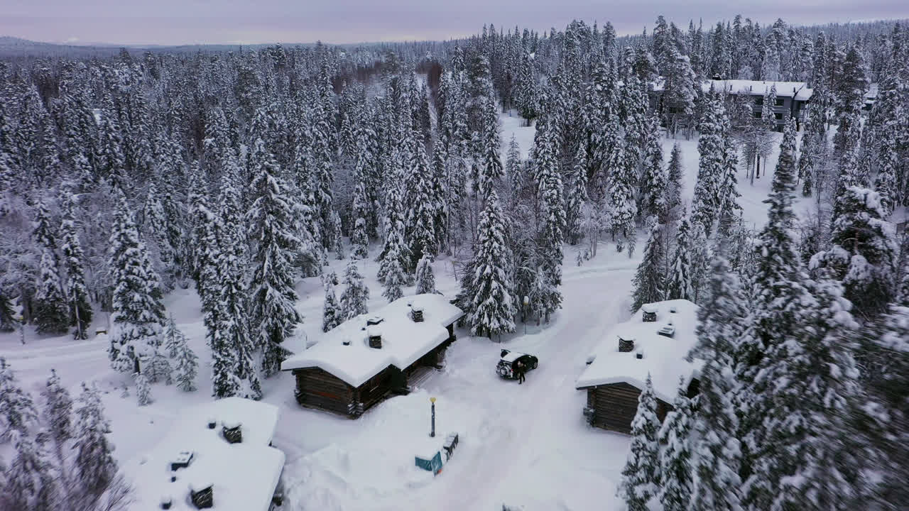 Aerial View of Snow-Covered Forest and Cabins in Winter