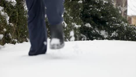 Slow-motion-low-angle-of-person-walking-in-deep-white-snow-after-snowfall-in-winter