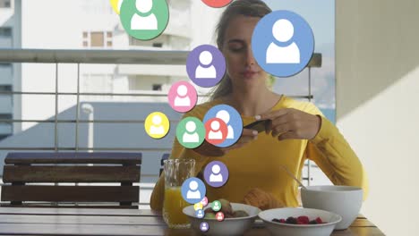 animación de iconos de las redes sociales sobre una mujer caucásica tomando fotos del desayuno con un teléfono inteligente
