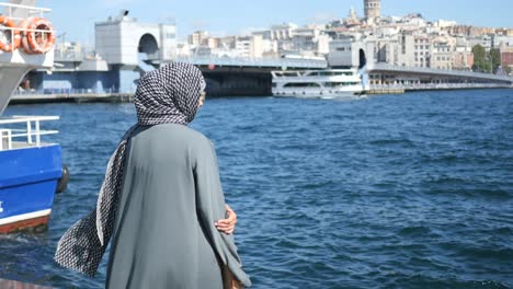 a woman in hijab standing near the galata tower in istanbul