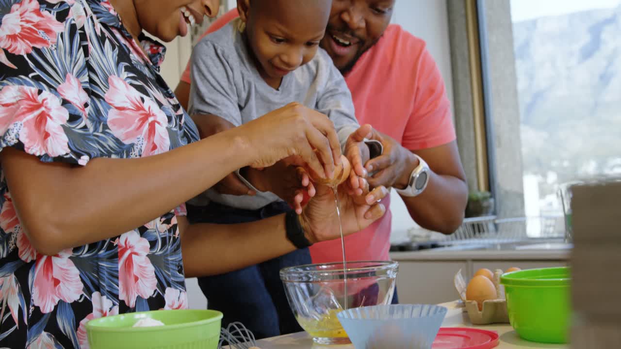 Parents and son cracking egg in kitchen at home 4k