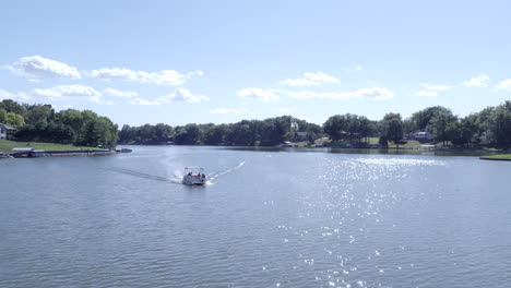 Flying-toward-boat-driving-on-a-lake,-aerial-drone