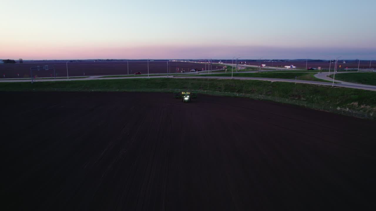 Tractor turning soil in Wisconsin, USA. Sunset aerial