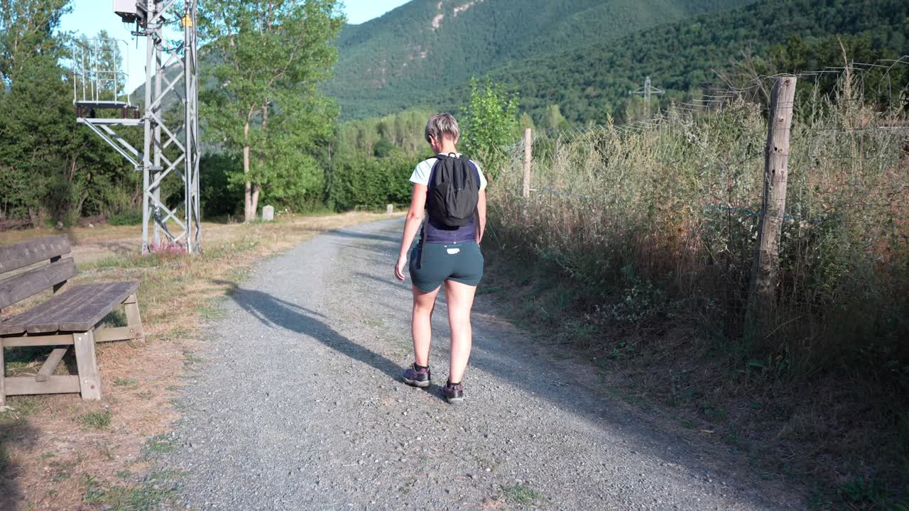 Mujer caminando por un camino de grava en una zona rural
