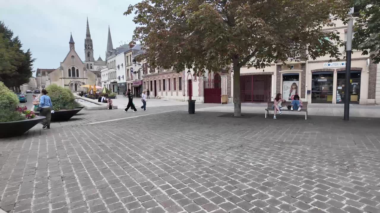 Crossing the road on foot and walking towards cathedral towers in Chartres, France.