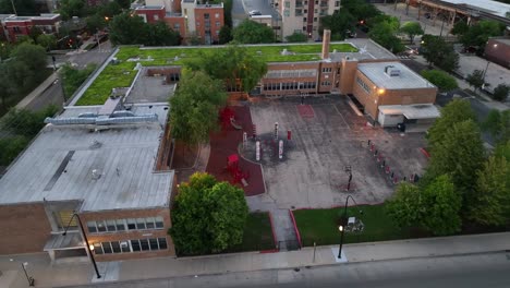 escuela urbana con patio de recreo y techo verde al anochecer en américa