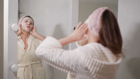 woman applying a face mask in her bathroom