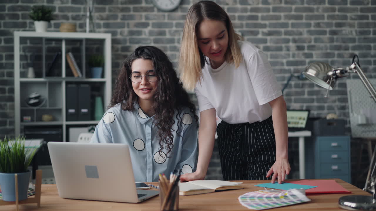 Two Women Collaborating on a Laptop in a Modern Office