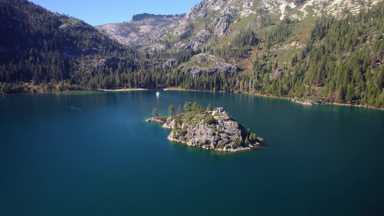 Imágenes de dron alejándose de la Isla Fannette, revelando el paisaje completo de Emerald Bay y las montañas circundantes.