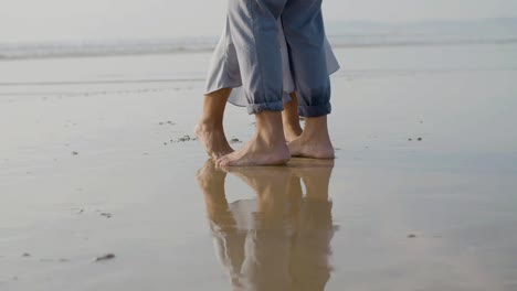 Legs-closeup-of-Caucasian-couple-dancing-on-wet-sand-at-seashore