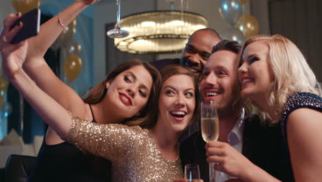 smiling group of friends celebrate evening event with selfie at party