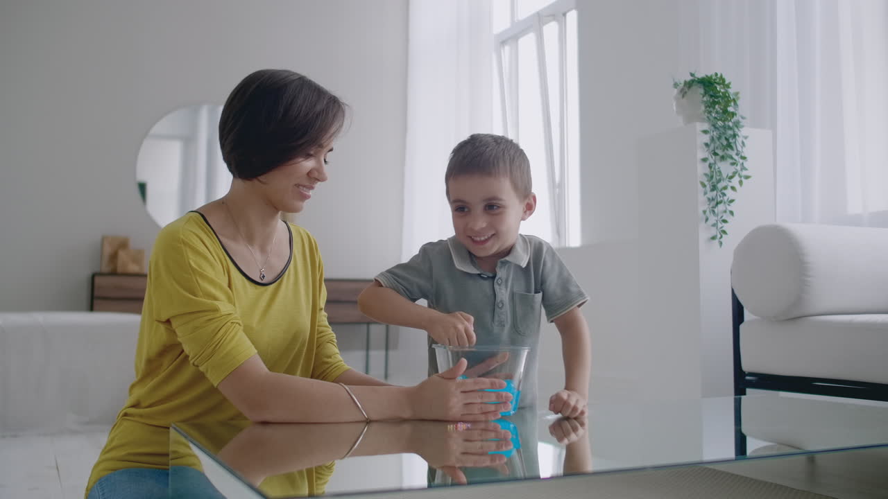 feliz y riendo madre e hijo juegan juntos con un lizun un juguete estirable líquido.