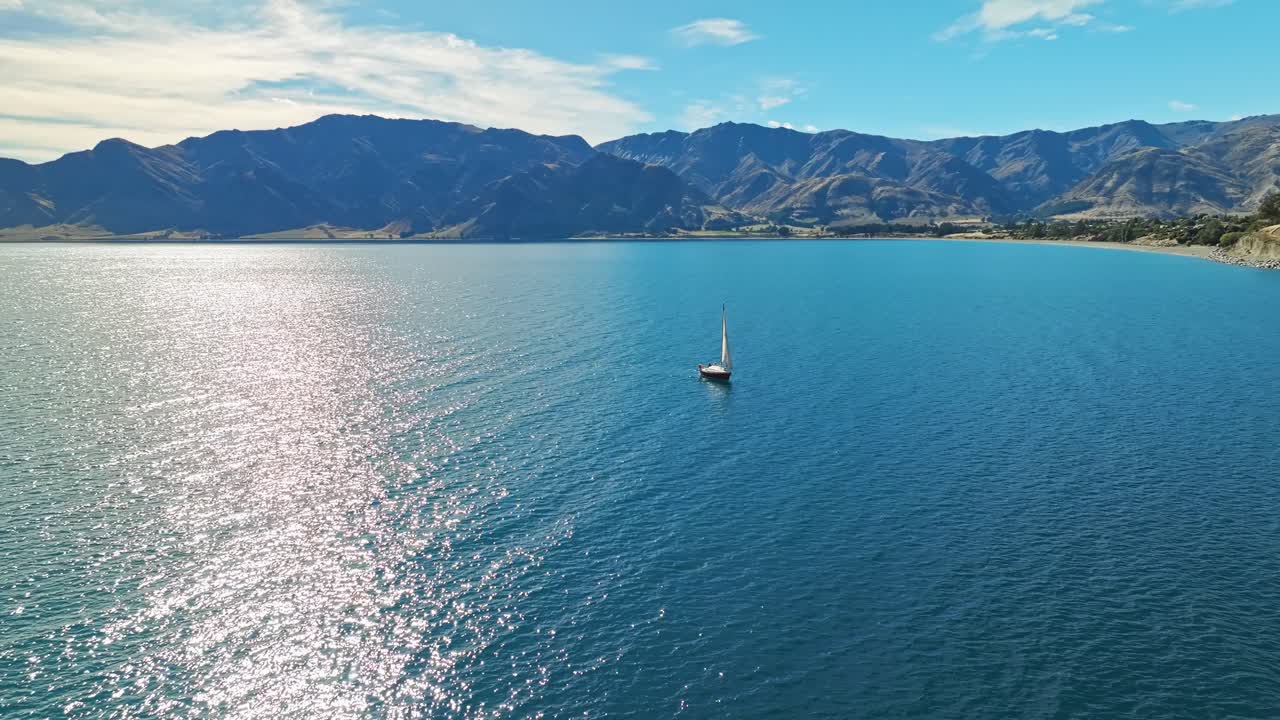 la órbita aérea de ángulo alto desciende mientras el rayo solar brilla a través del barco de vela