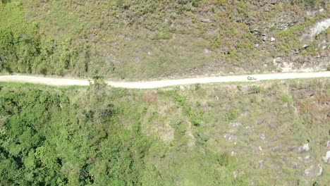 Car-driving-along-a-straight-rural-road-along-mountain-forest