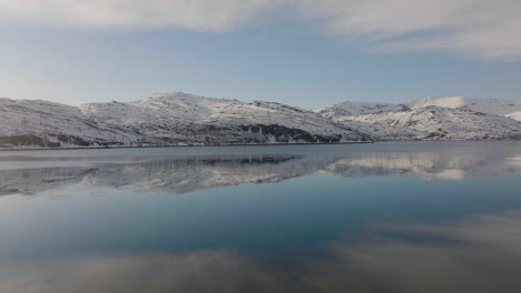 Montañas-Nevadas-Con-Reflejos-De-Cielo-Azul-En-Un-Hermoso-Lago-Tranquilo-En-Dafjord,-Ringvassoya,-Norte-De-Noruega