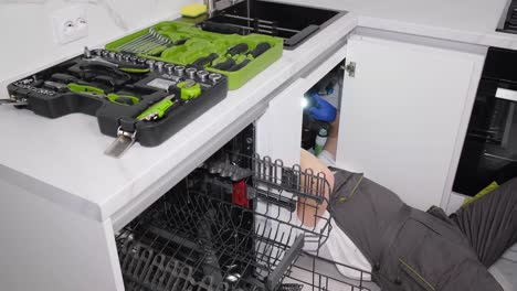 a plumber works lying on the floor in the kitchen he installs a sink the work of a plumber