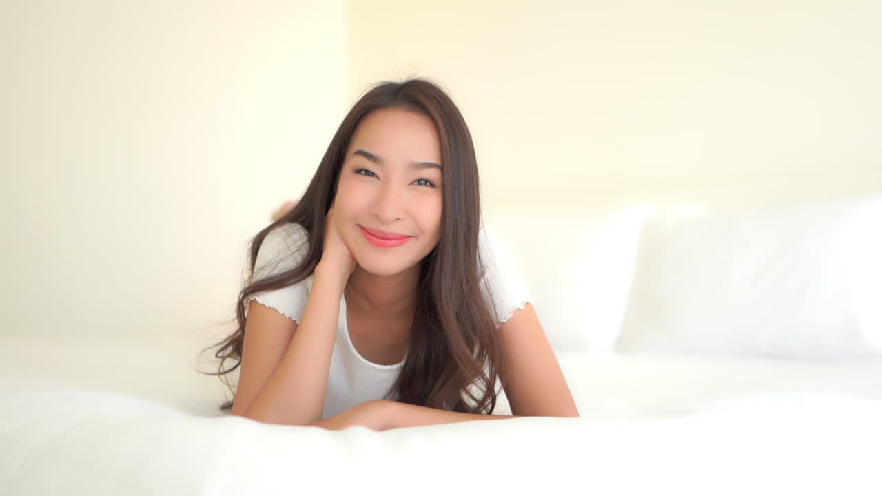 그녀의 뱃속에 큰 편안한 침대에 누워있는 매력적인 젊은 여성의 느린 팬