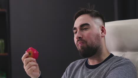 hombre hambriento sentado en el escritorio y comiendo una manzana roja 1