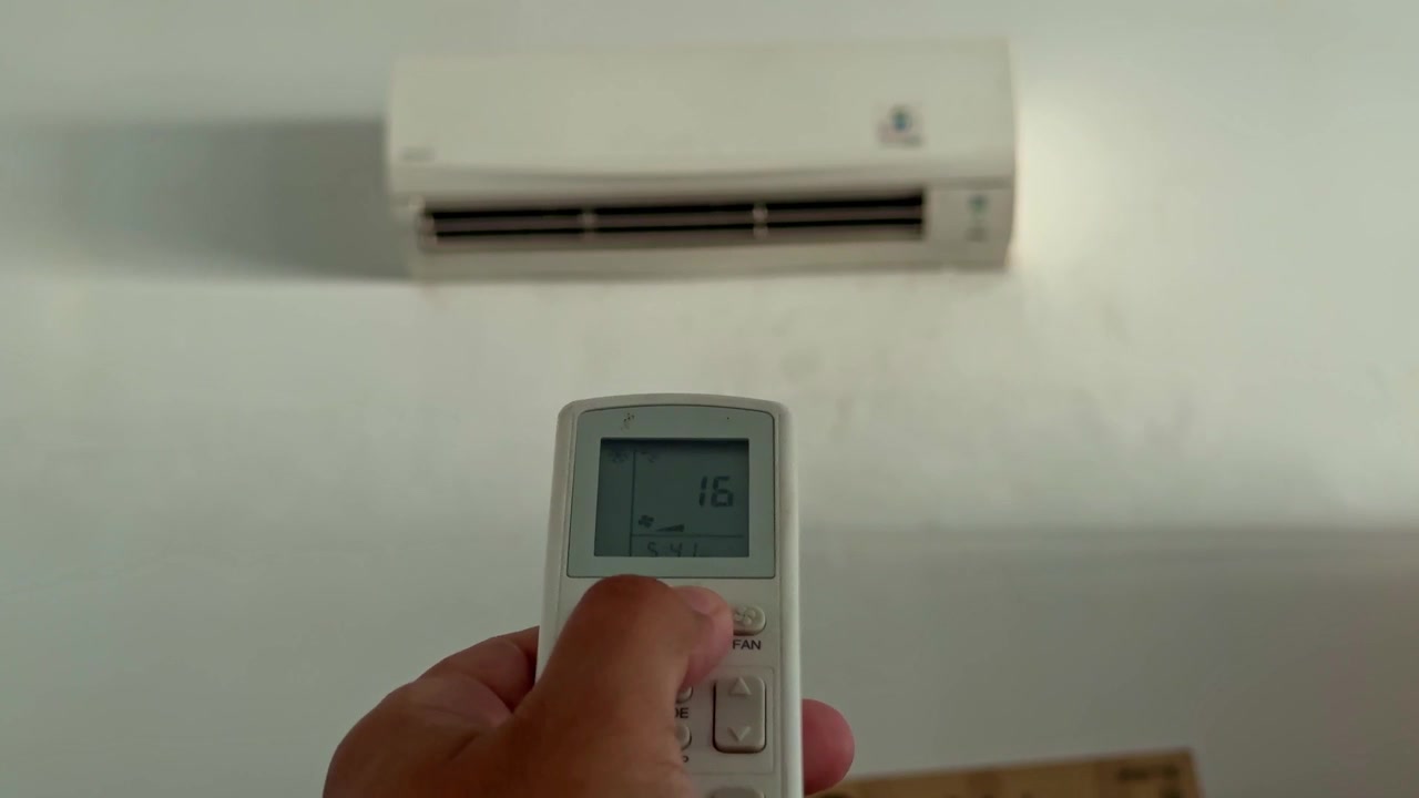 Mano che preme il pulsante del telecomando del condizionatore per accendere e controllare la temperatura della stanza, sistema di raffreddamento interno, filmato di elettrodomestici