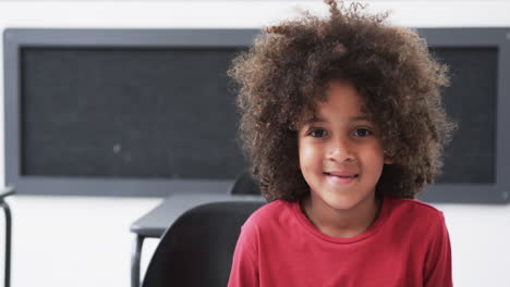 in a school classroom, a young african american boy smiles warmly with copy space