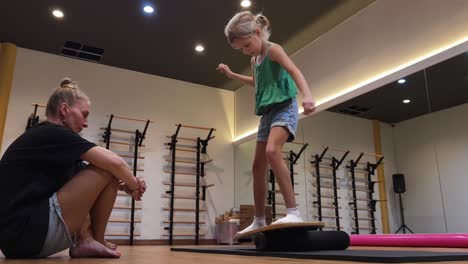 child learning balance on a balance board with an instructor