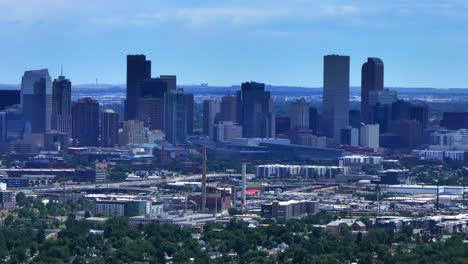 Summer-downtown-Denver-city-skyscrapers-Colorado-aerial-drone-static-shot-traffic-cars-highway-Mile-High-neighborhood-homes-blue-skies-cloudy-6th-avenue-colfax-RTD-line-front-range-foothills-landscape