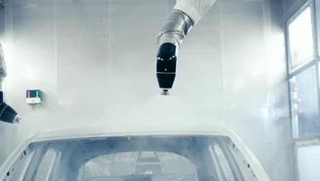 brazos robóticos pintando con spray un cuerpo de vehículo en una fábrica de fabricación de automóviles