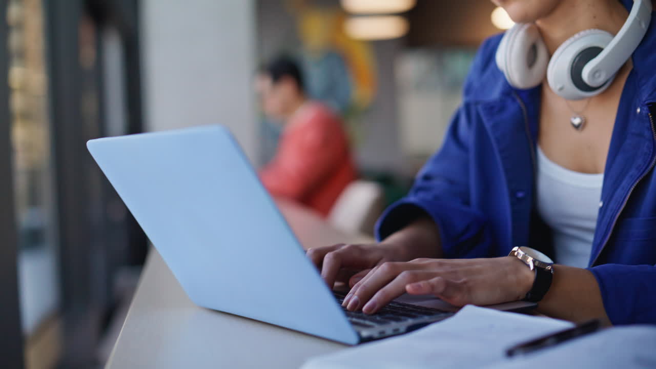 Two students working laptops at cafeteria space. Focused man typing computer