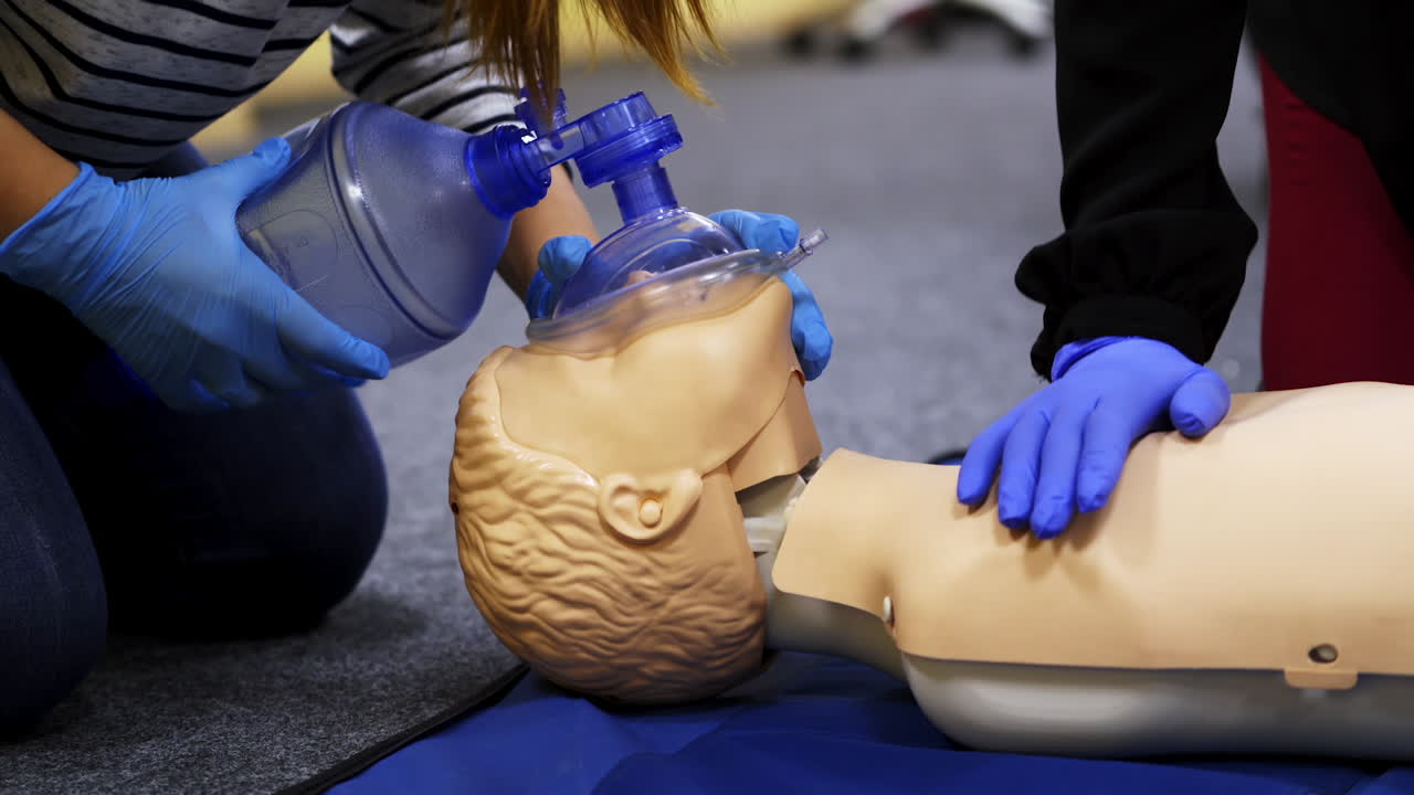 Training course on a manikin. Practitioners giving breath exercises on a dummy at resuscitation. Compression during heart attack on a mannequin.