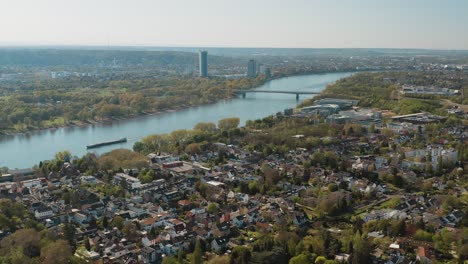 Drone---Toma-Panorámica-Aérea-De-Bonn-Con-El-Puente-Konrad-Adenauer,-El-Río-Rin-Con-Un-Barco,-El-Gran-Hotel-Kameha-Y-La-Torre-De-Correos-30p