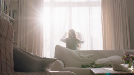 happy little girl opening curtains looking out window at beautiful new day with bright sunlight playful child feeling positive about future