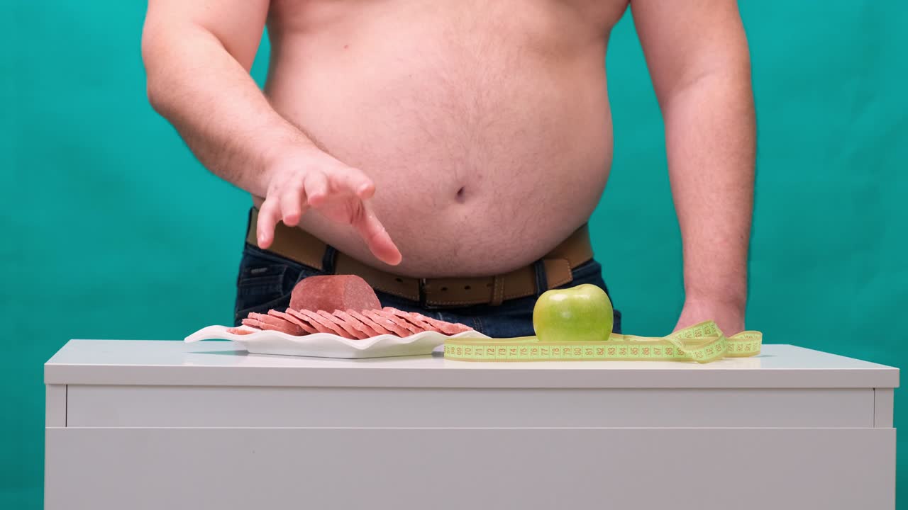 un hombre con un vientre gordo elige entre una salchicha y una manzana verde. el concepto de dieta y fuerza de voluntad